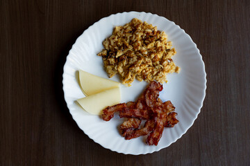 scrambled eggs, bacon and cheese on a white plate, a full healthy and tasty breakfast, energy for the whole day