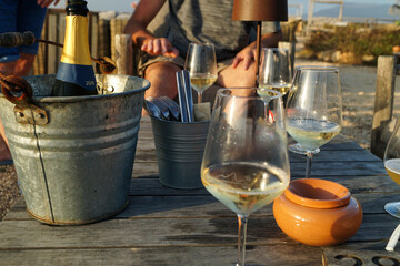 Tavolo aperitivo bar all'aperto con bottiglie e bicchieri di vino bianco prosecco 