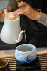Pour hot water from the tea into the matcha bowl. A warm cup of matcha is made of finely ground green tea powder