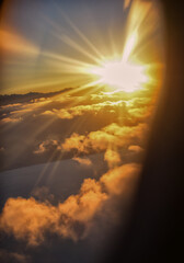 a plane window with the sun shining through the clouds.