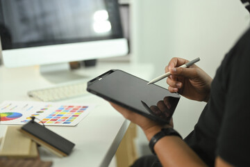 Cropped shot male designer or or creative professional using digital tablet and stylus to work on a...