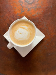 A cup of cappuccino on a rough, aged metal background