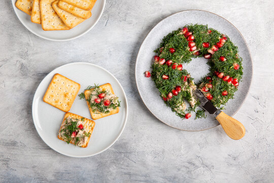 Tuna pate decorated with dill and pomegranate seeds in shape of wreath served with crackers.