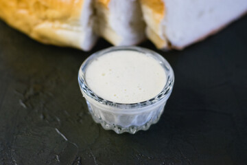 Delicious homemade mayonnaise sauce. Mayonnaise in a glass saucer and appetizing white bread on a...