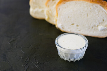 Delicious homemade mayonnaise sauce. Mayonnaise in a glass saucer and appetizing white bread on a...