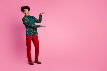 Full size photo of optimistic cheerful guy with wavy hair dressed print shirt hands showing empty space isolated on pink color background