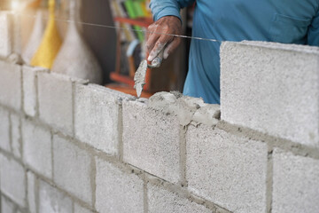 masonry worker make concrete wall by cement block and plaster at construction site
