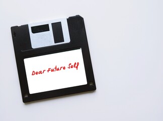 Floppy disk on copy space white background with tag DEAR FUTURE SELF, letter to convey message to...