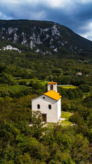 Aerial view of a small white chapel surrounded by lush green hills