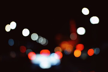 Abstract blur lights night in the city background. Rain drop on the windshield, Bokeh of traffic lights and tail lights, Blurred abstract background