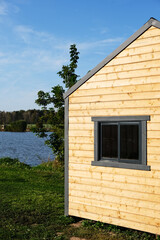 house facade with wood paneling on grass, tree and lake