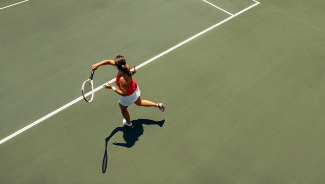 Aerial view of female tennis player executing a forehand on court - Powered by Adobe