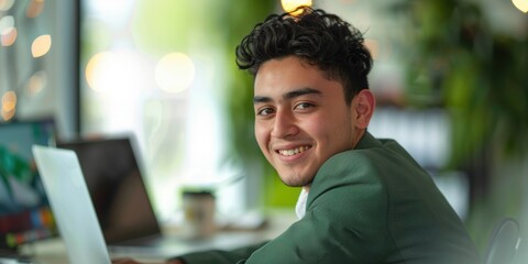 Confident young mixed race entrepreneur utilizing a laptop at a desk in an office. Driven leader focused on achieving success through dedication and effort in a startup environment