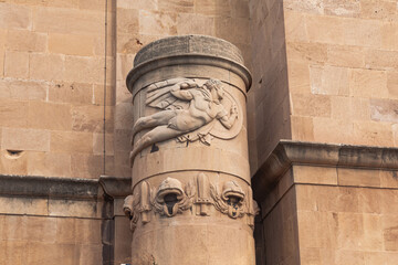 The facade of an old building with a column with bas-reliefs.