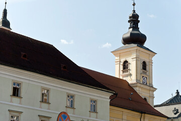 A baroque-style church tower in Sibiu, Romania, featuring an onion-shaped dome, a clock face, and arched windows.