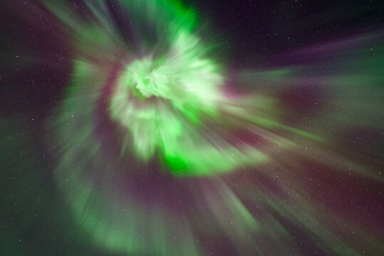 A bright green, pink, red and purple auroral corona, northern lights in Tromso, Norway. Aurora borealis with lots of stars - Powered by Adobe