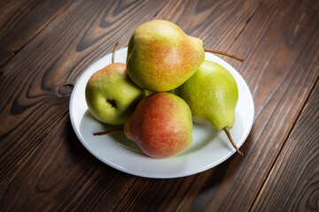 Fresh pears on plate on wooden background. Selective focus