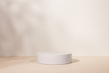 Empty white stage made with white circle shape podium on a beige backdrop.