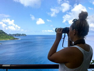 Obraz premium A woman using binoculars to observe nature and wildlife from a lookout point in Fernando de Noronha, Brazil