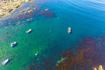 small fishing boats anchored in a small natural harbor on a rocky coastline in summer
