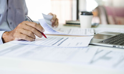 Asian businessman reviewing document reports at office workplace. legal expert, professional lawyer reading and checking financial documents or insurance contract before sign