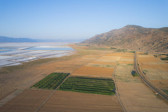 Aerial view of serene salt farm plots and fields with a mountain backdrop, Dazkiri, Turkey.