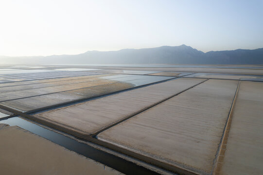 Aerial view of serene salt farm fields with beautiful patterns and textures surrounded by mountains, Dazkiri, Turkey.
