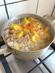 The soup is cooked on the stove. Food is cooked in an old aluminum pot. Hot soup on the stove.