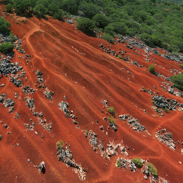 Aerial view of dunas de pacula with red earth, vegetation, and rugged hills, Pacula, Mexico.