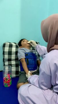 A child living with swallowing disorders is undergoing a speech therapy session in the speech therapy room. rubbed with a training toothbrush lesson