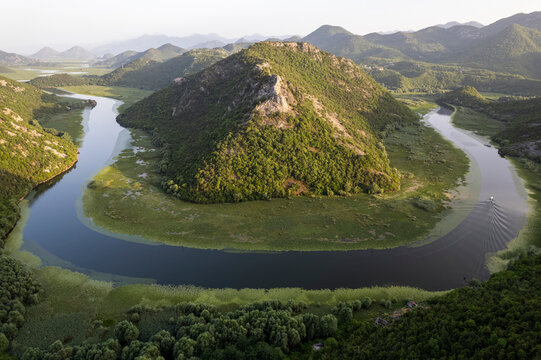 Aerial view of the winding river through a lush valley surrounded by majestic mountains, Rijeka Crnojevica, Montenegro.