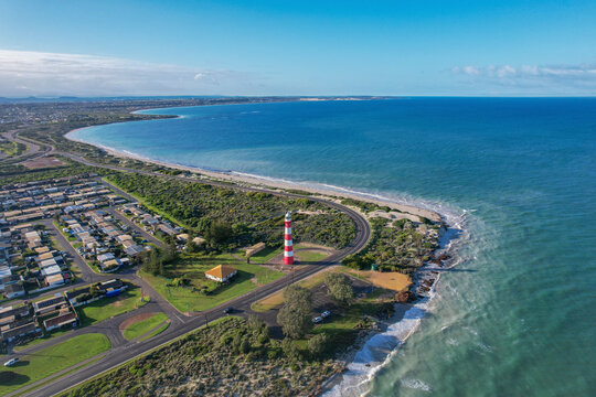 Aerial view of Point Moore Lighthouse and sandy coastline with houses and ocean, Geraldton, Australia.
