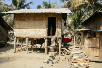 Traditional bamboo and wood made house of Bangladeshi tribal people, a chakma kid is standing on...