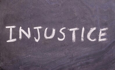 Fototapeta premium Injustice Word Written on Blackboard with White Chalk