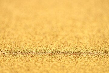 Beautiful golden glitter sparks texture as background with shallow depth of field