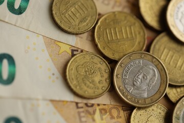 Many cent coins of euro currency lies on many fifty euro bills banknotes
