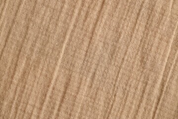 Texture of crumpled linen fabric under natural light in peach fuzz color