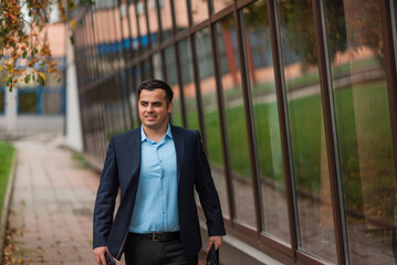 A happy young business man walking in the city street near the office building.