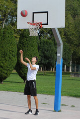 Boy playing basket ball on outdoors basket court.	