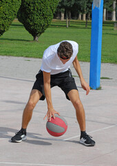 Boy playing basket ball on outdoors basket court.	