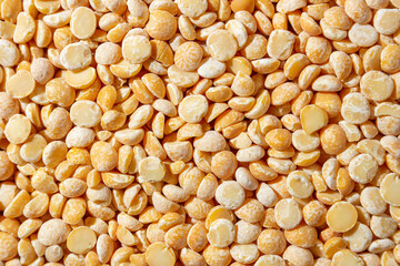 Uncooked Polished Split Peas Background. A Culinary Canvas of Dry Yellow Peas, Creating a Lively and Textured Background for Gourmet Cooking. Scattered Raw Polished Peas. Healthy Eating Ingredients