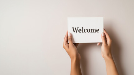 Hands of different skin tones offering a "Welcome" card against a neutral backdrop, inclusivity, minimalism, diversity, welcoming message