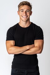Obraz premium A confident young man smiling with arms crossed, wearing a black t-shirt, set against a clean white background, evoking a sense of self-assurance and approachability