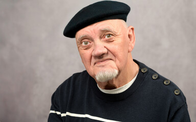 portrait vieil homme coiffé d'un béret sur fond gris