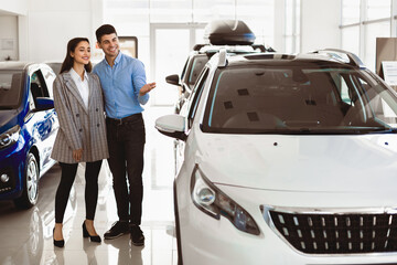 This Is What I Want. Young family standing at the dealership choosing the car to buy, full length