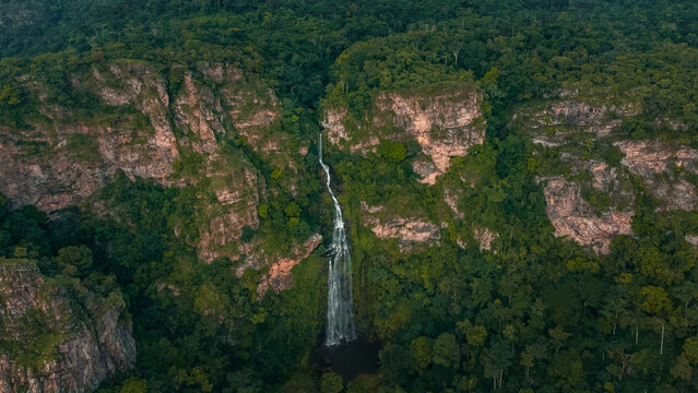 Aerial view of a majestic waterfall cascading down a lush cliff surrounded by tropical forest and greenery, Volta, Ghana.