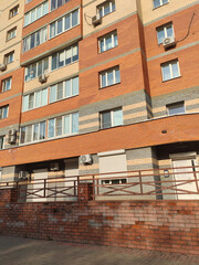 Naklejka premium modern building facade made of red and gray bricks, with windows, air conditioning units, and a simple entry. This design reflects the practical and straightforward architecture found in urban