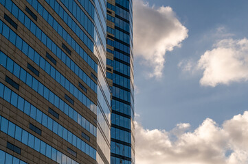 Fototapeta premium Windows of building at sunset. Reflection of the sky in the window glass. Skyscrapers in business district against blue sky. Looking up high-rise office buildings. Angled view.