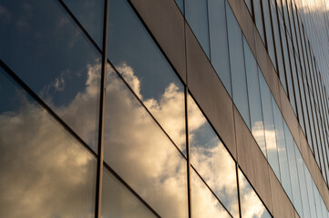 Windows of building at sunset. Reflection of the sky in the window glass. Skyscrapers in business district against blue sky. Looking up high-rise office buildings. Angled view. © sergio34