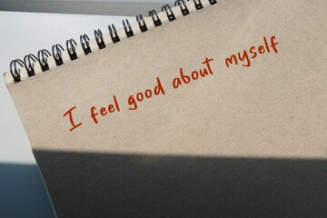 Brown notebook with handwritten text  I FEEL GOOD ABOUT MYSELF - Positive affirmation to boost self...